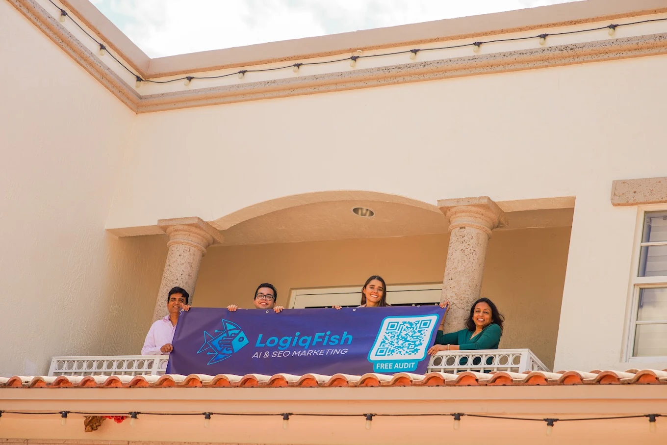 The LogiqFish team on the office balcony at Weston Town Center, holding a LogiqFish banner